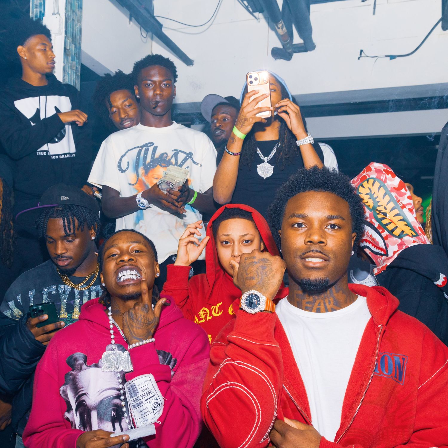 Group of young men in red and black outfits posing together at a lively indoor party event.