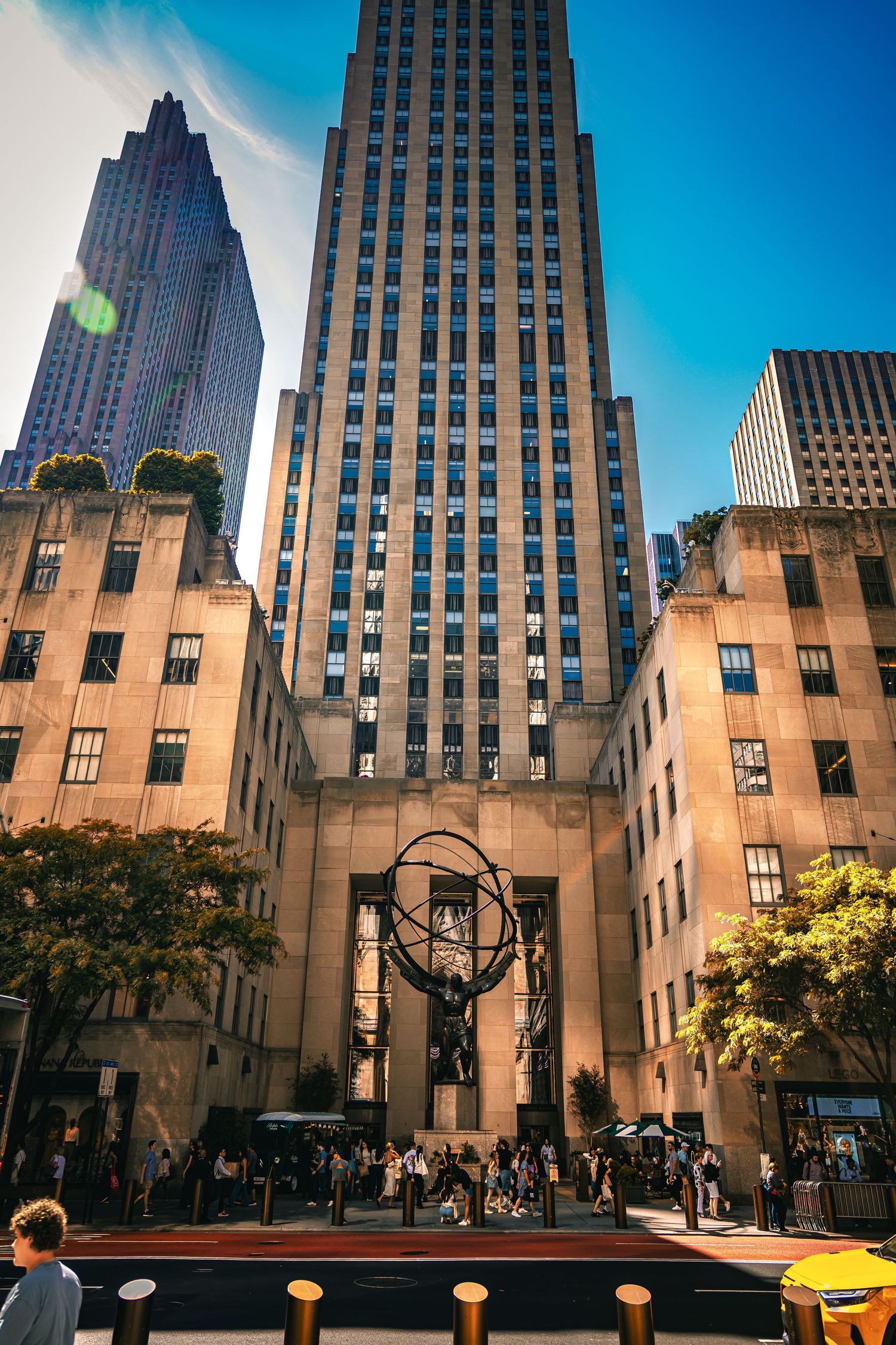 Atlas statue stands before Rockefeller Center's Art Deco skyscraper in Midtown Manhattan, New York City, on a sunny day.
