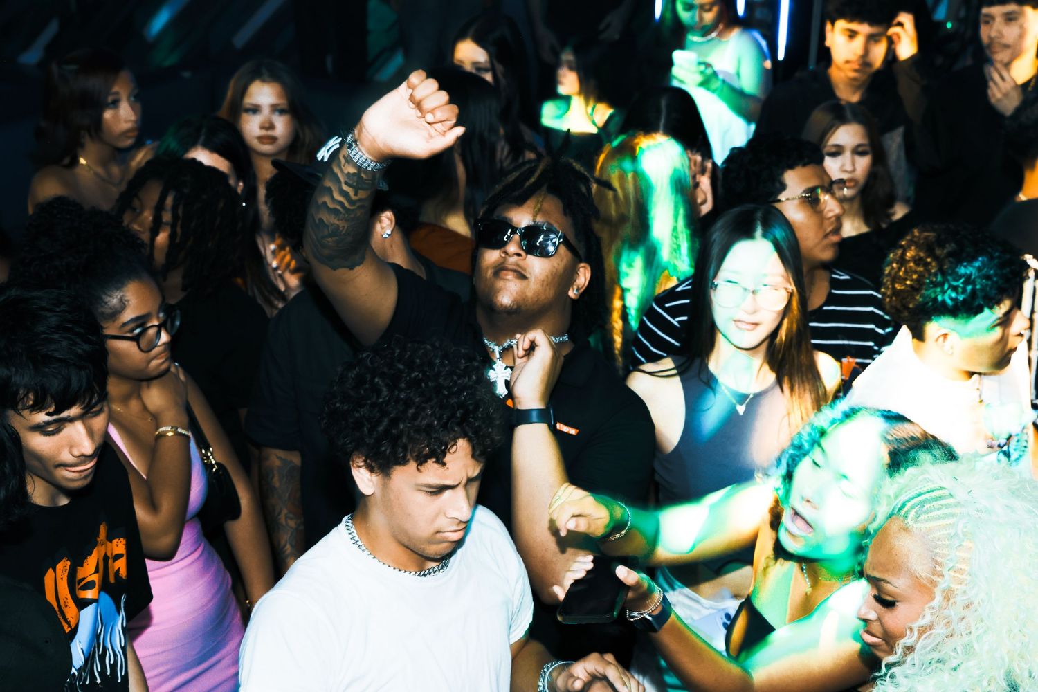 Diverse crowd of young people dancing and socializing at a lively nightclub party event.