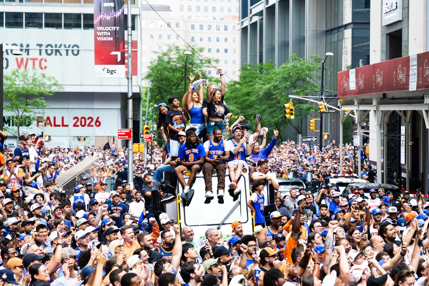 Massive crowd celebrates at a victory parade with athletes on a float in a bustling city street.