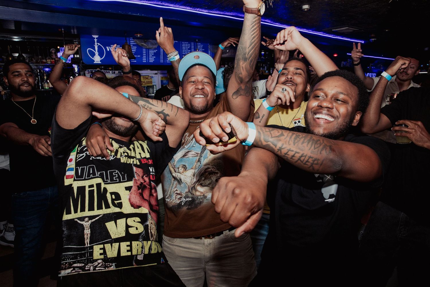 Energetic crowd of people celebrating and dancing at a lively nightclub party event.