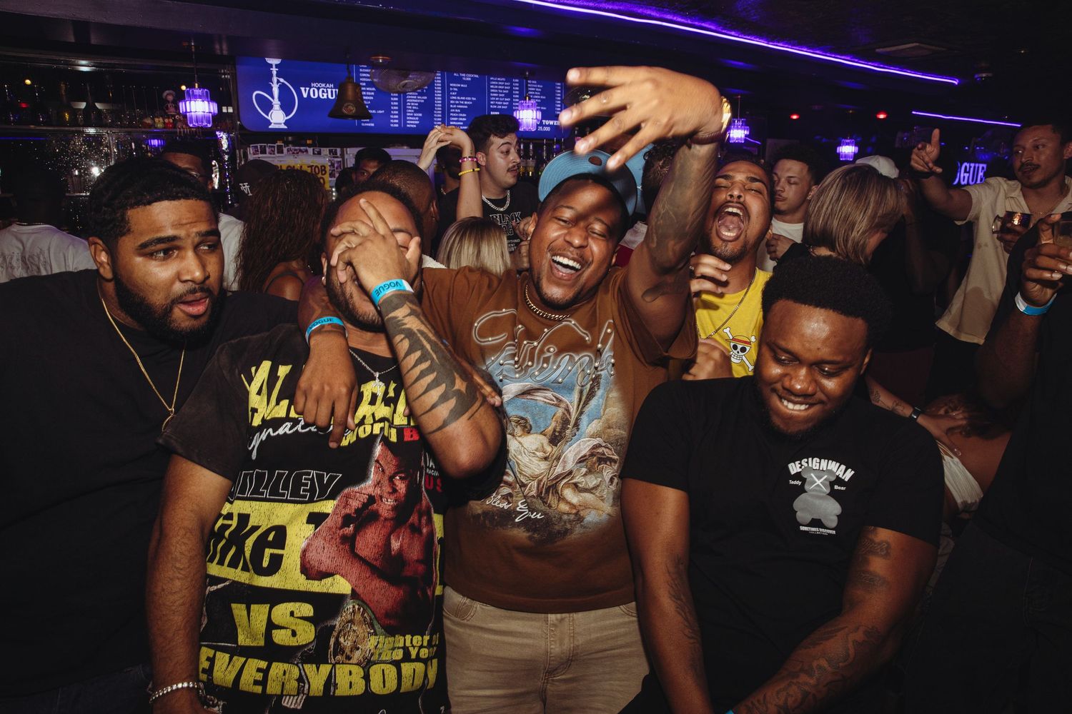 Excited crowd celebrating together at a vibrant indoor bar or nightclub event.