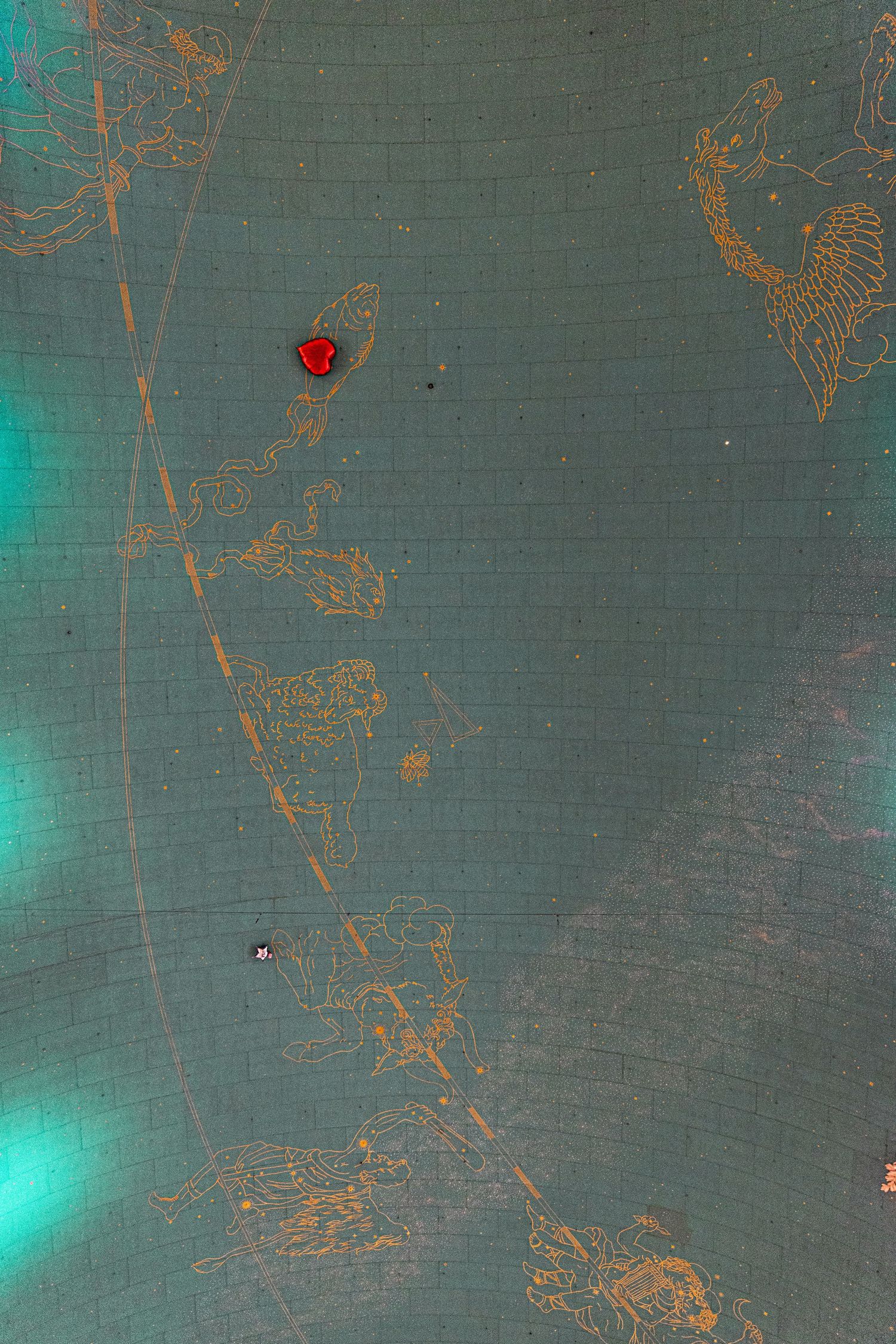 Antique teal globe surface with golden etched map engravings and red gemstone accent detail.