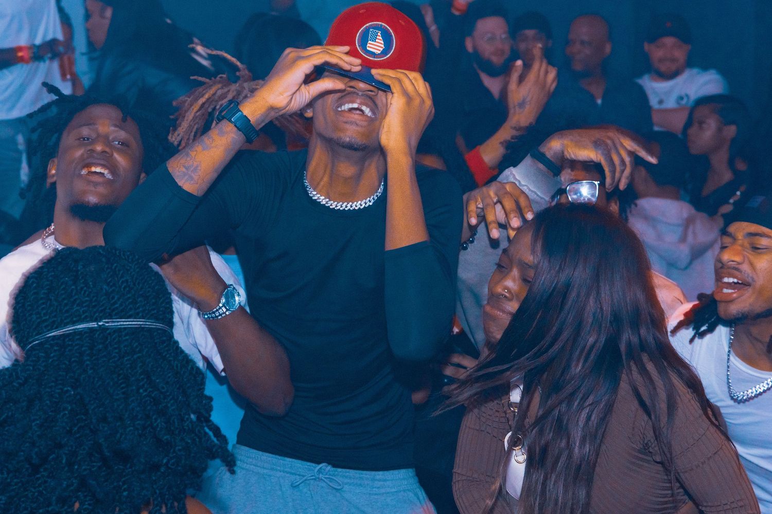 Energetic crowd dancing and celebrating at a lively nightclub party under blue lights.