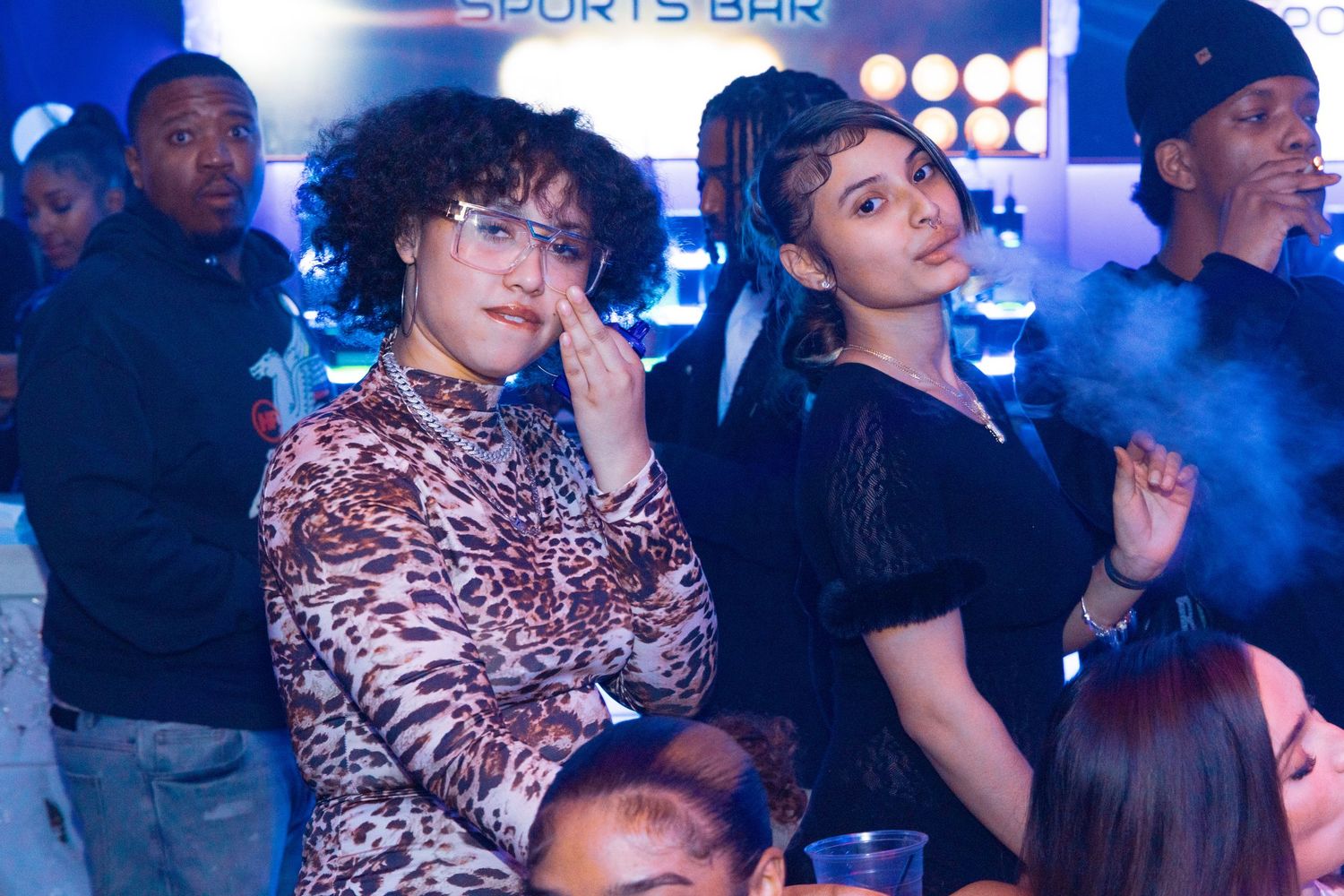 People socializing at a sports bar nightclub with blue ambient lighting and a lively atmosphere.