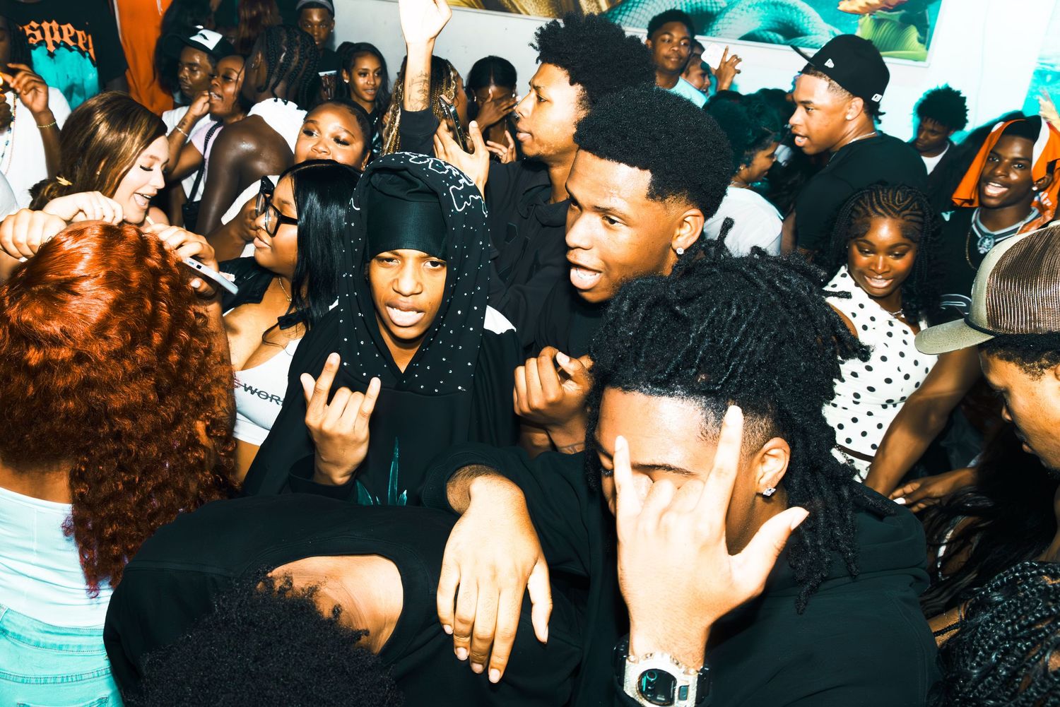 Young people dancing and socializing at a lively indoor party event with colorful lighting.