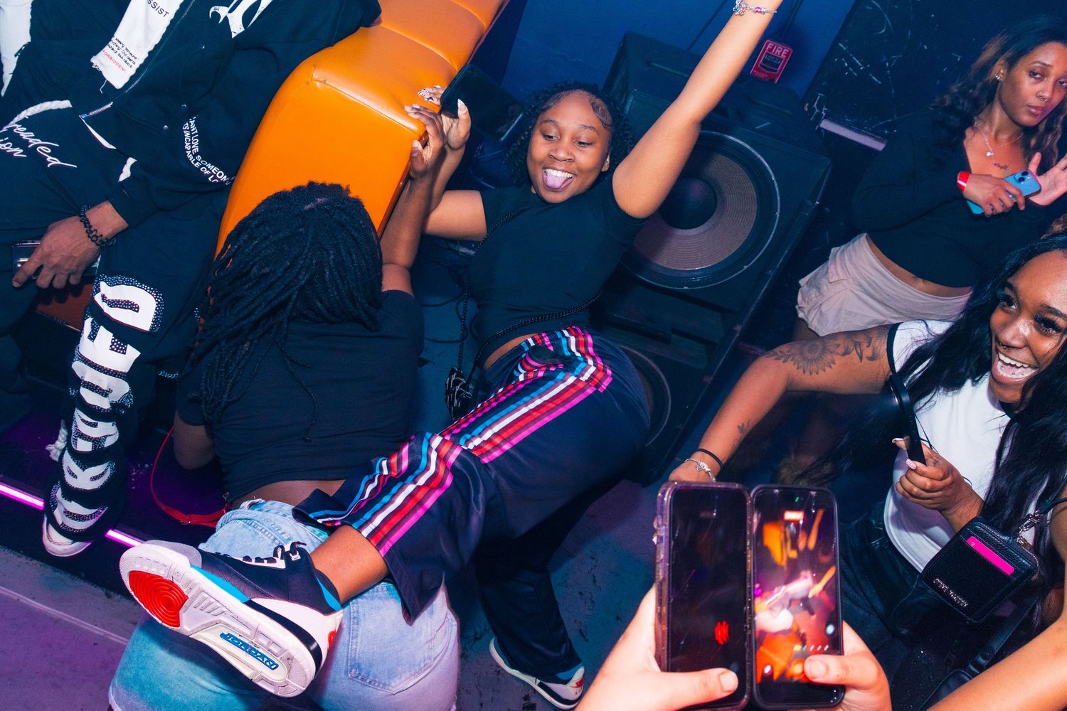 Group of young women dancing and having fun at a nightclub party with speakers in the background.