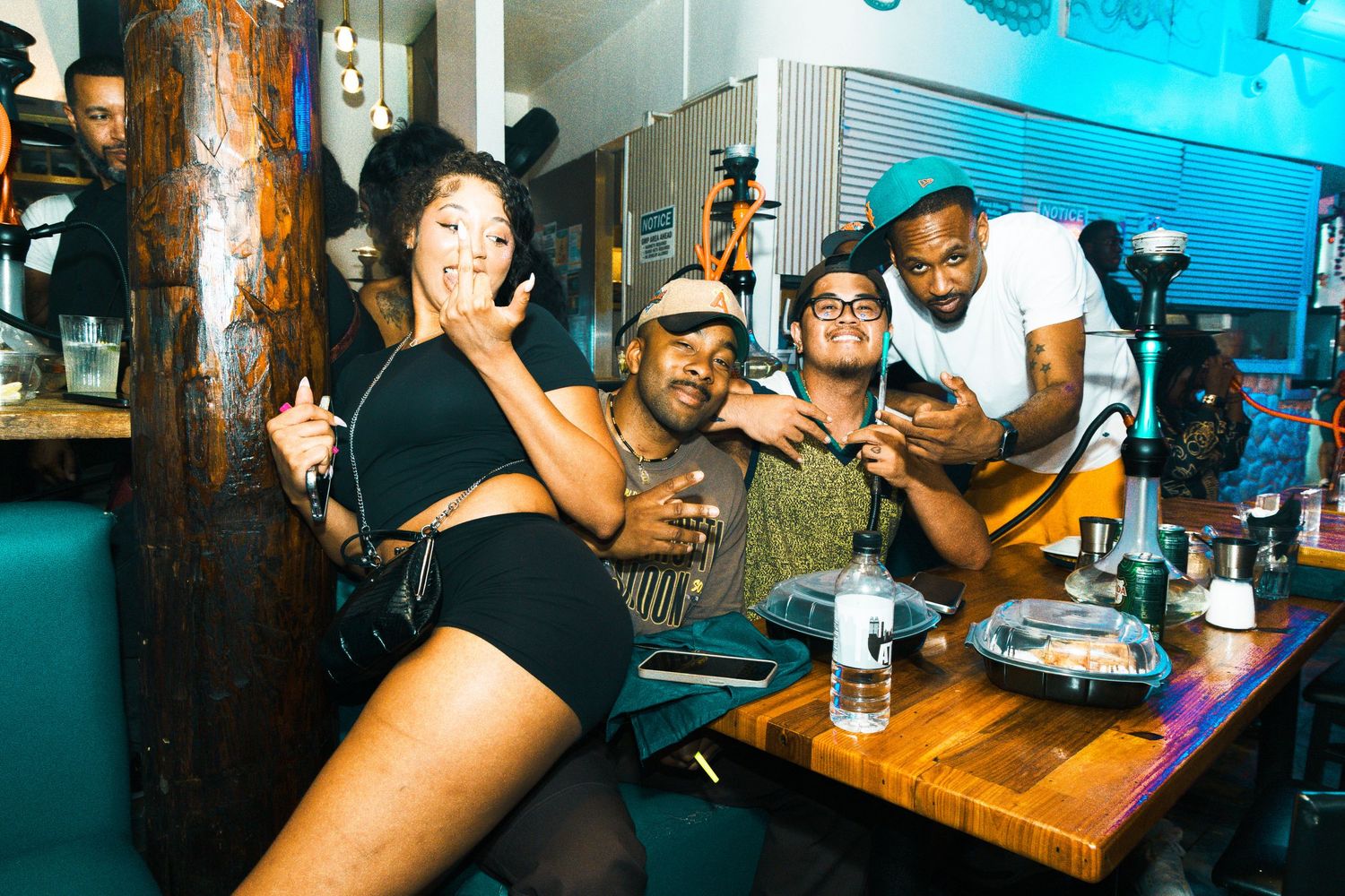 Group of friends smiling and posing together at a lively bar or nightclub setting.
