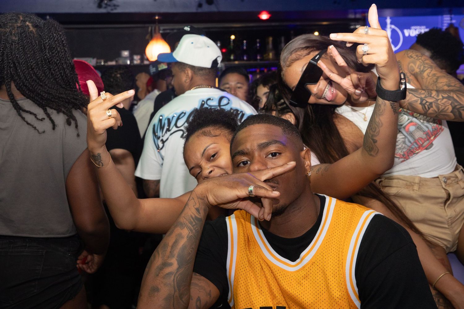Group of young adults posing and having fun together at a crowded nightclub.