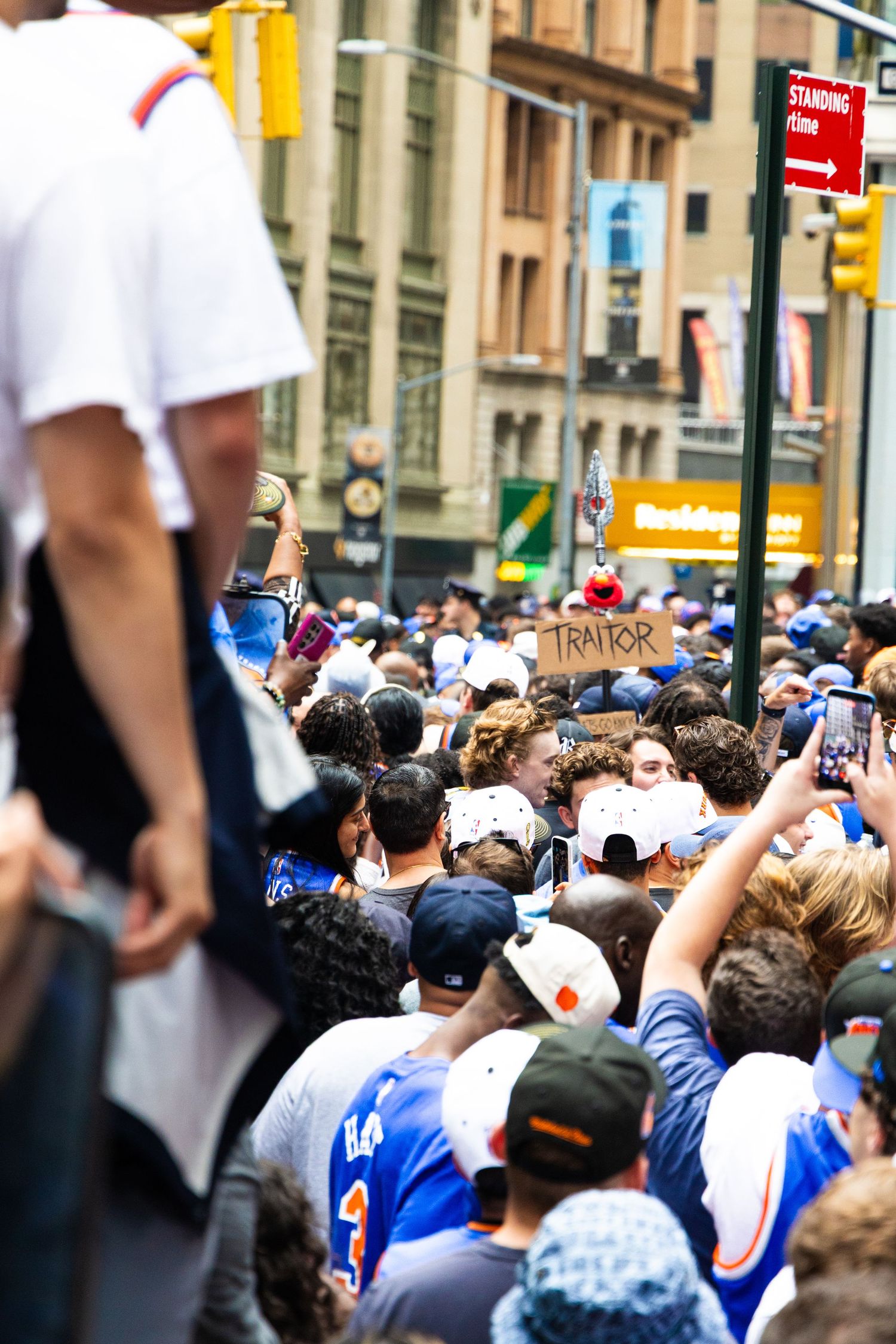Large crowd at NYC street parade, fans in blue jerseys hold a 