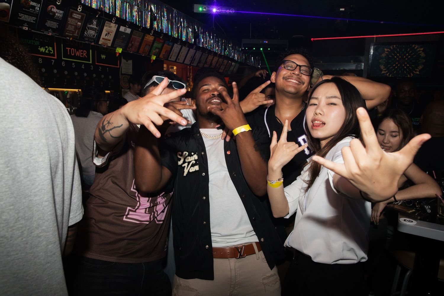 Friends posing and making hand gestures together at a fun nightclub event.