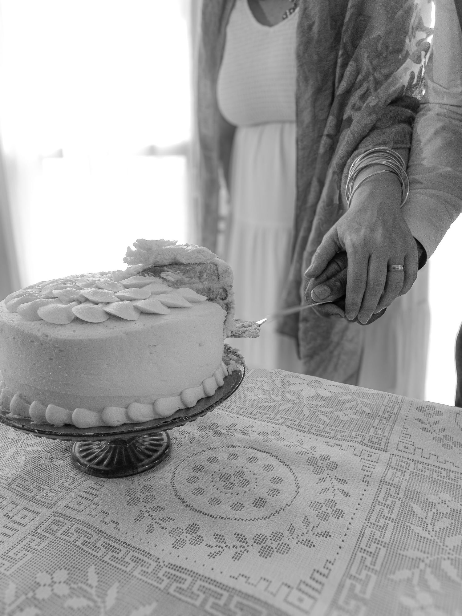 Black and white images showing hands cutting a cake on a lace tablecloth in sequence.