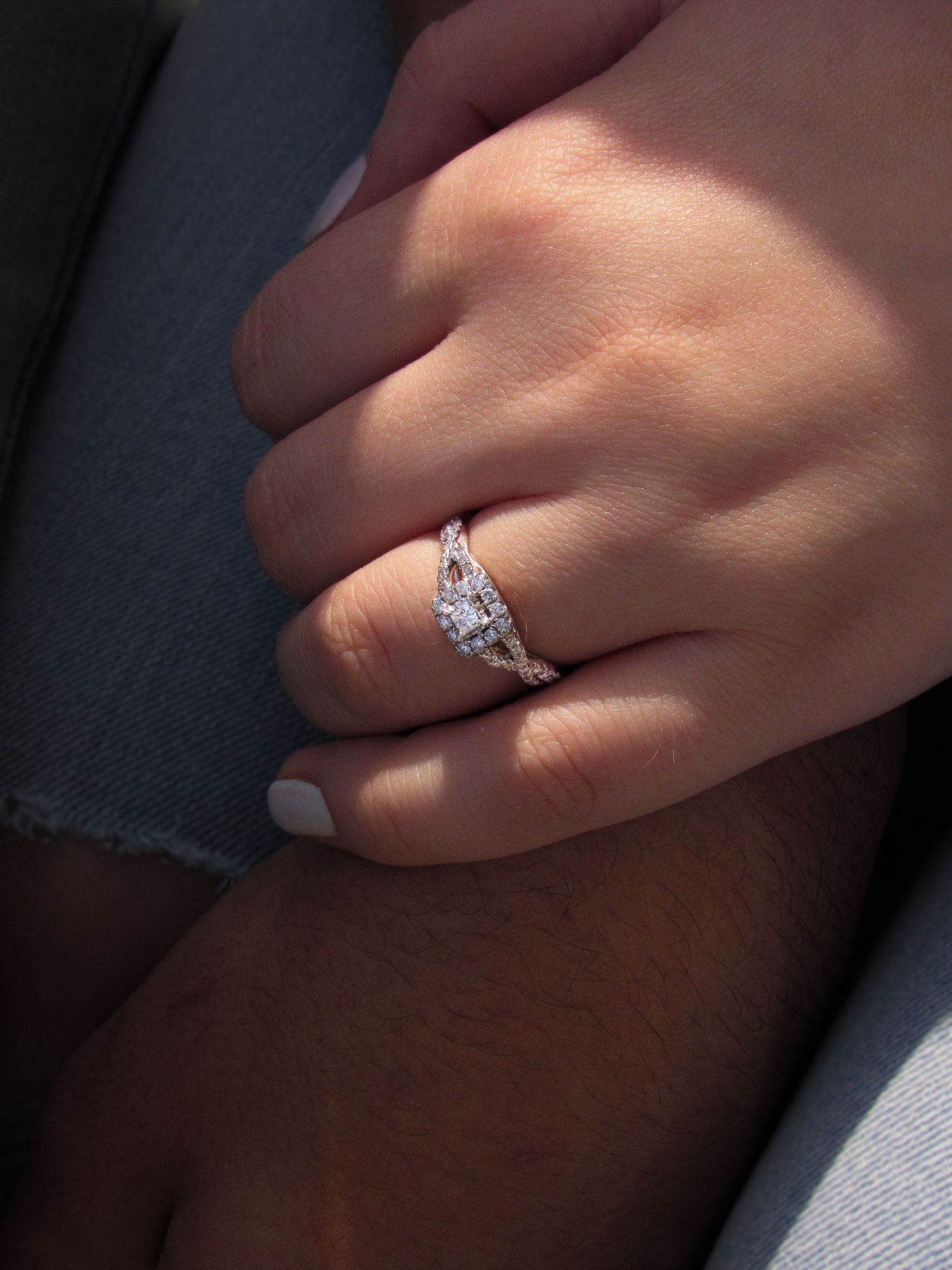 Close-up view of sparkling diamond engagement ring on hand with sunlight creating a beautiful shimmer effect.