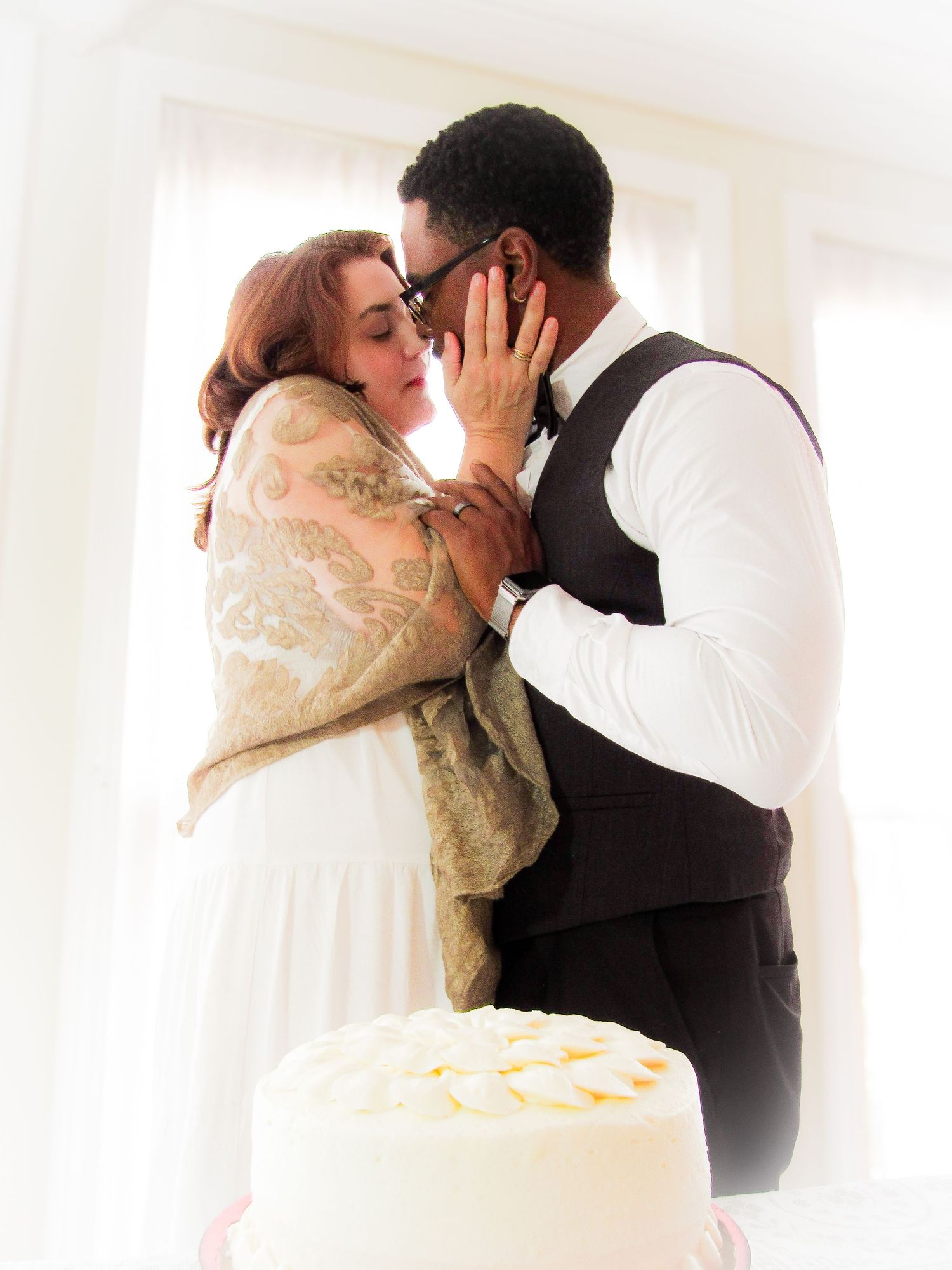 Soft focus sequence of a romantic wedding kiss with a white wedding cake in the foreground.