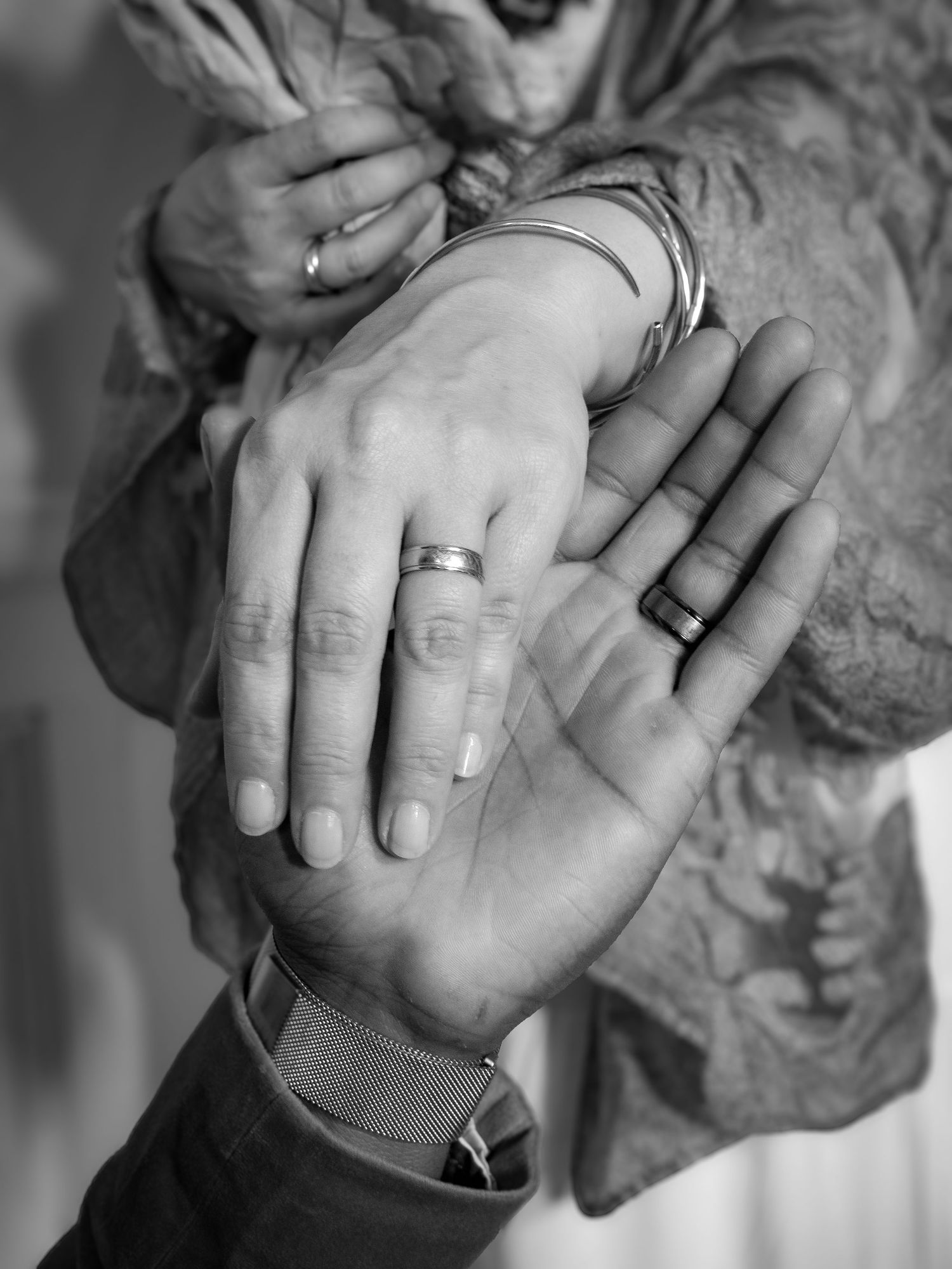 Black and white close-up photo series showing clasped hands with wedding rings.