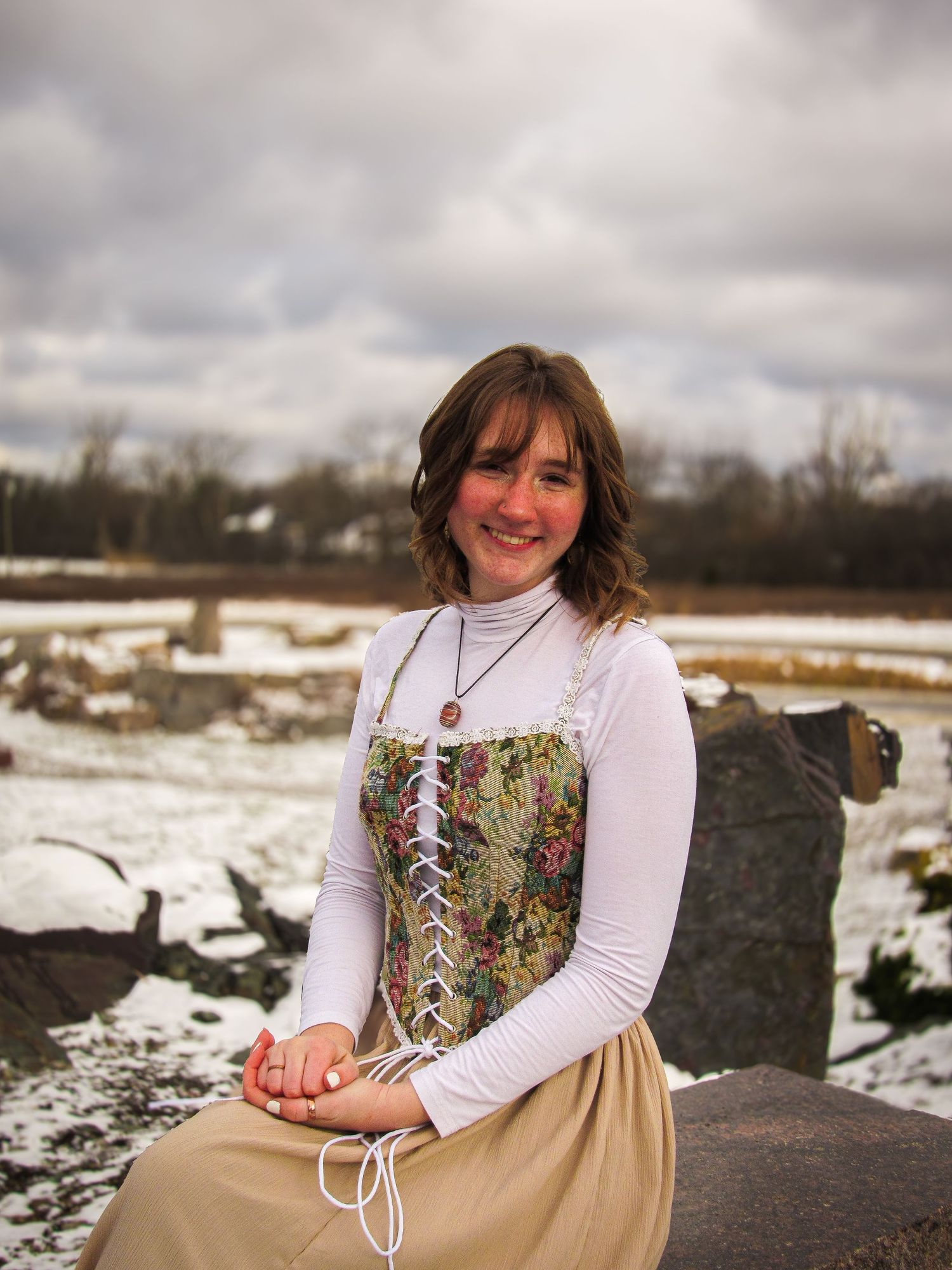 Winter portrait session on snowy rocks with scenic background.