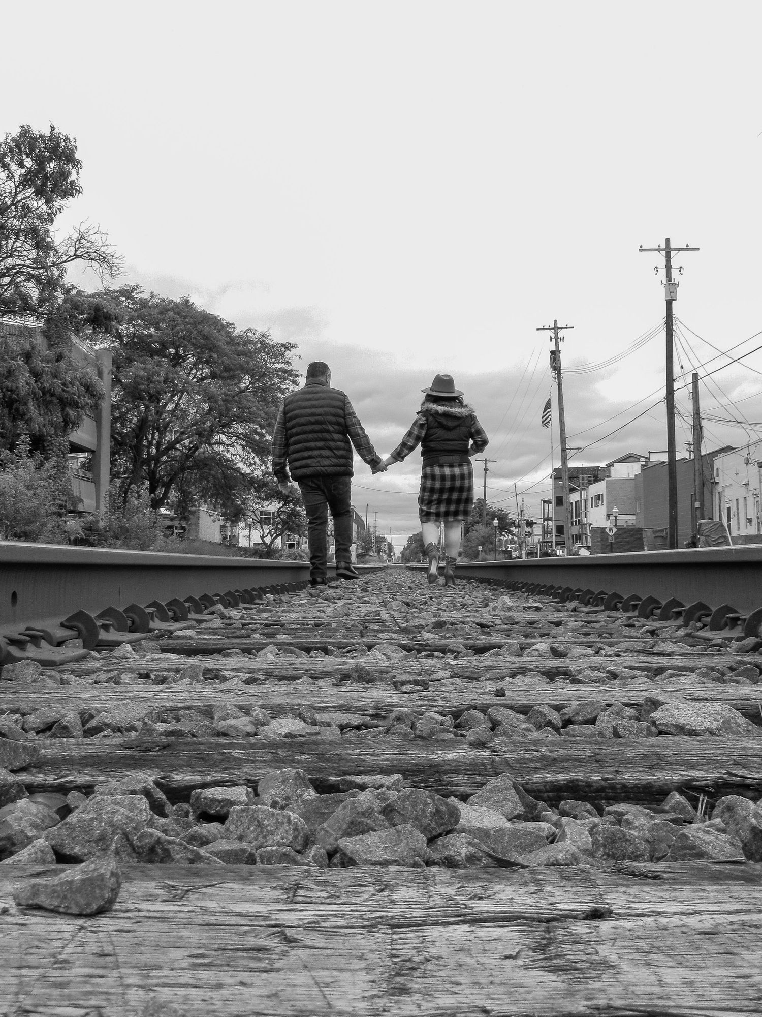 A black and white photo captures two figures walking along railroad tracks.