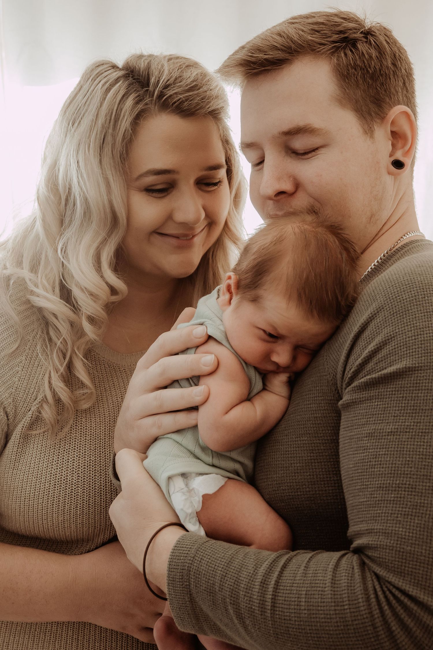 Mother and father embracing their newborn baby during an in home central coast newborn photoshoot.