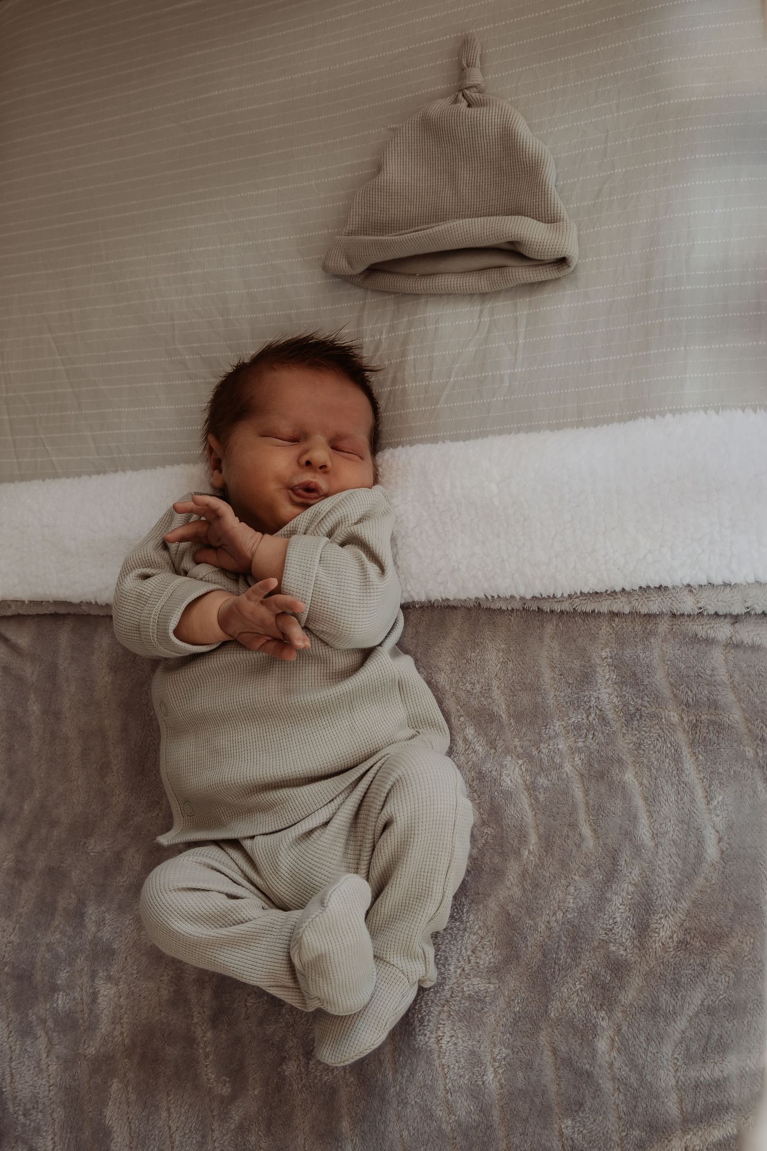 Newborn baby in their crib scrunched up at a central coast newborn photoshoot.