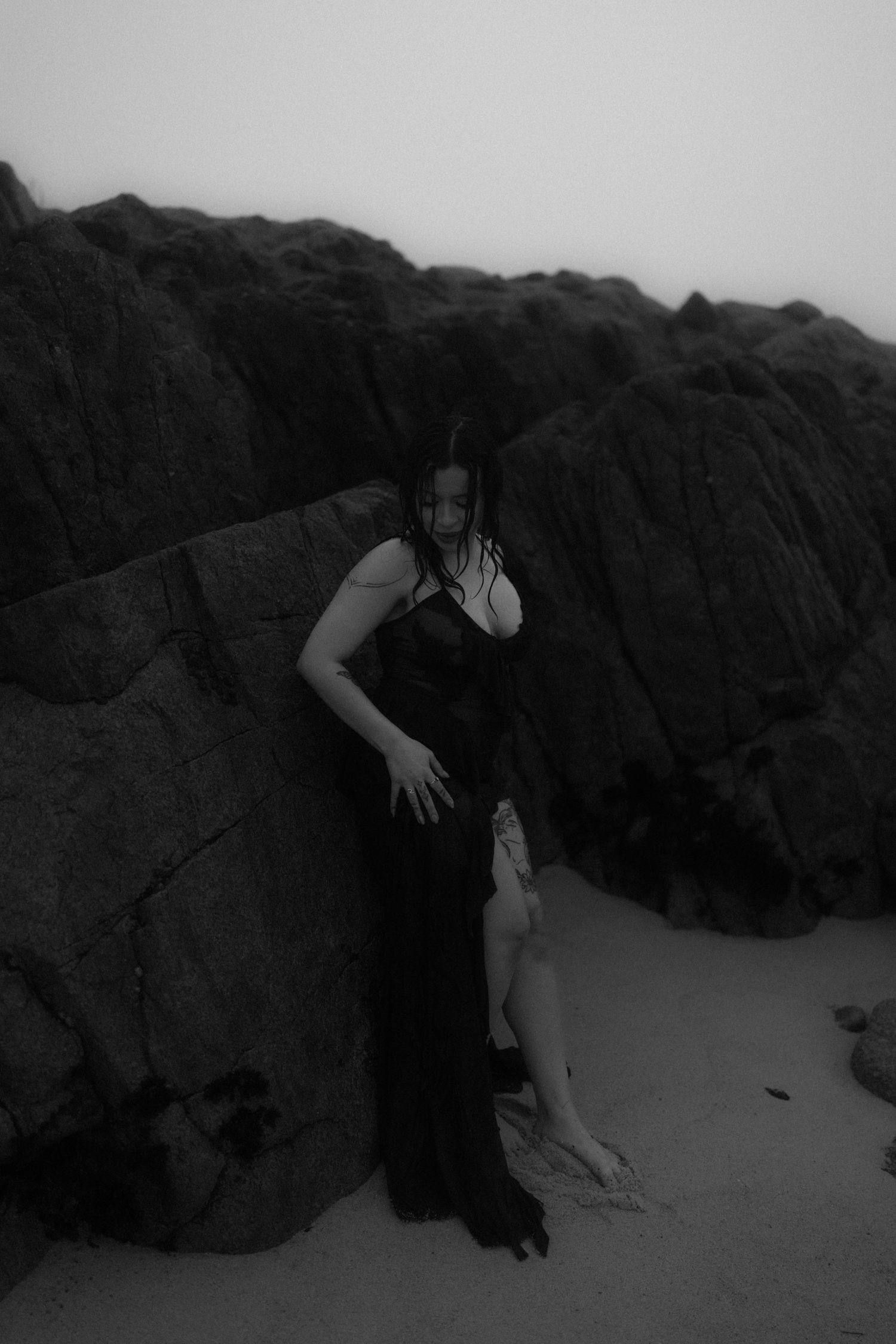 Ethereal figure in dark clothing moving dramatically against rocky coastal backdrop.