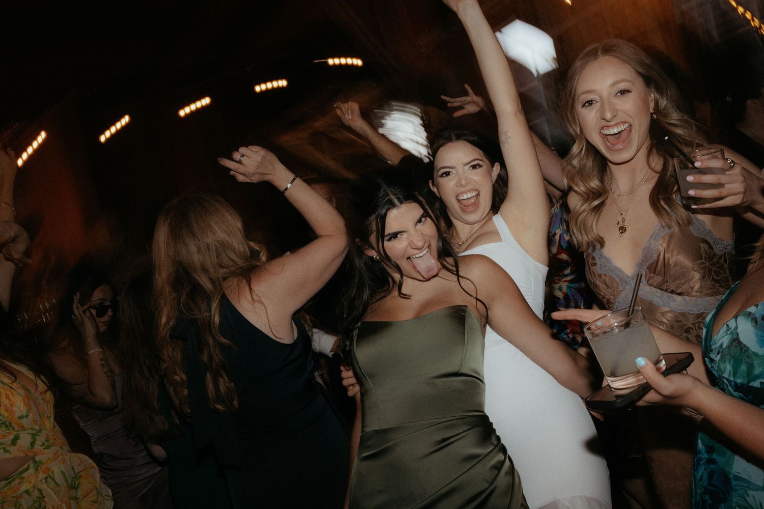 A group of people dancing and celebrating at a lively nighttime party or reception.