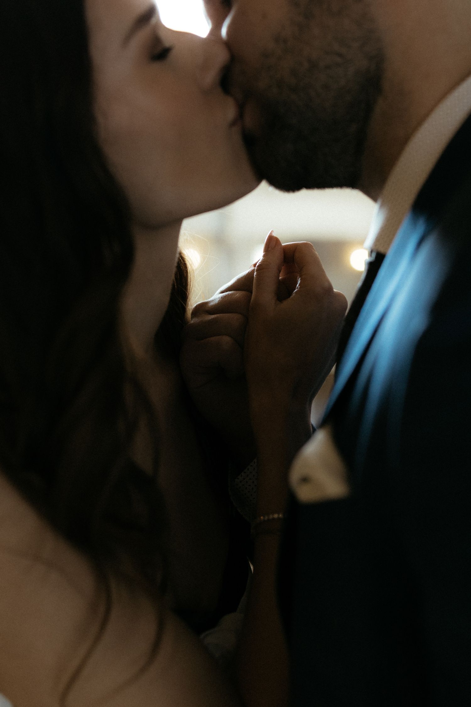 Close-up silhouette shot of a couple sharing a tender kiss in dramatic lighting.