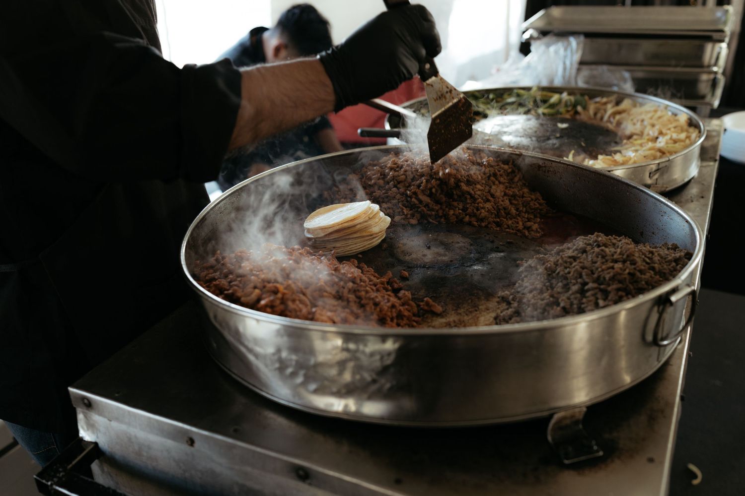Large paella pans cooking traditional Spanish rice dishes at an outdoor event.