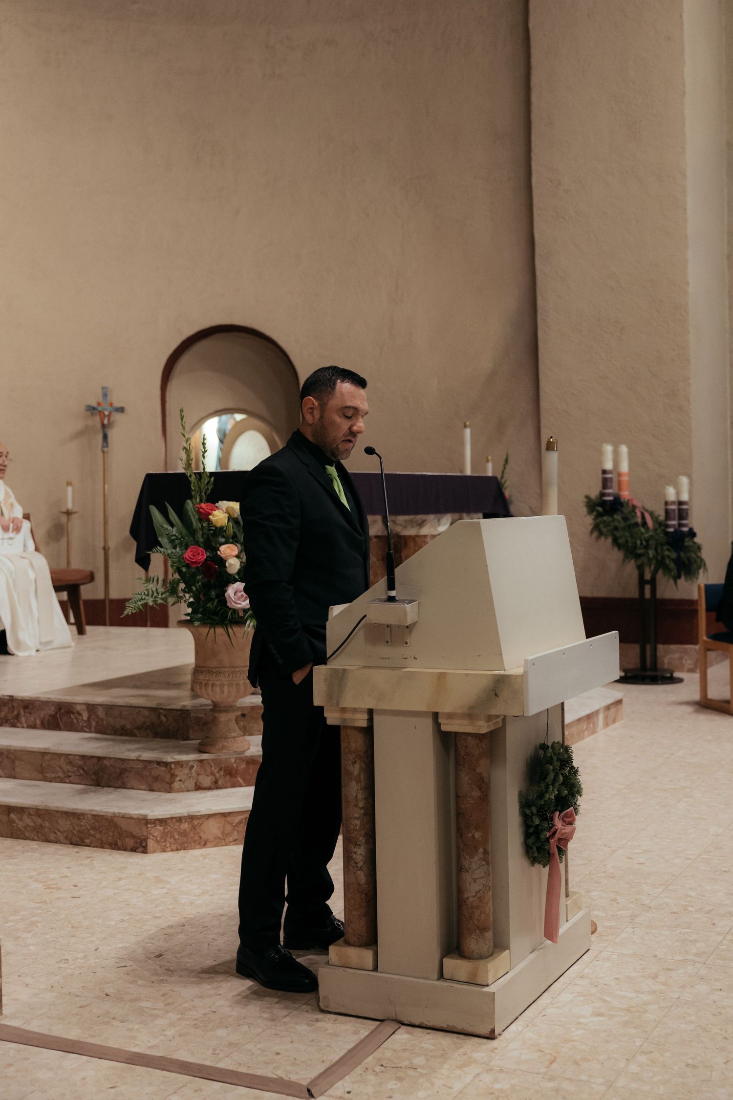 A speaker stands at a white podium during a church ceremony.