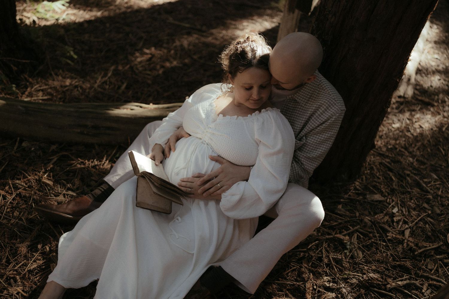 Intimate forest photography session with couple embracing among towering redwood trees.