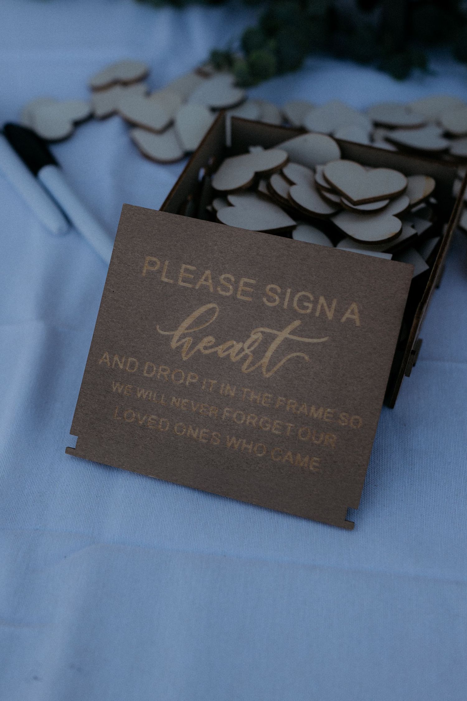 Wooden wedding guest book signs with elegant calligraphy text displayed on a light blue surface.