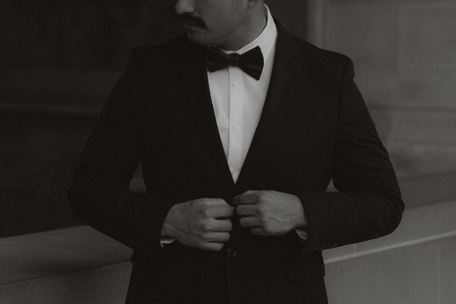 Moody black and white portrait series featuring formal attire against stone walls.