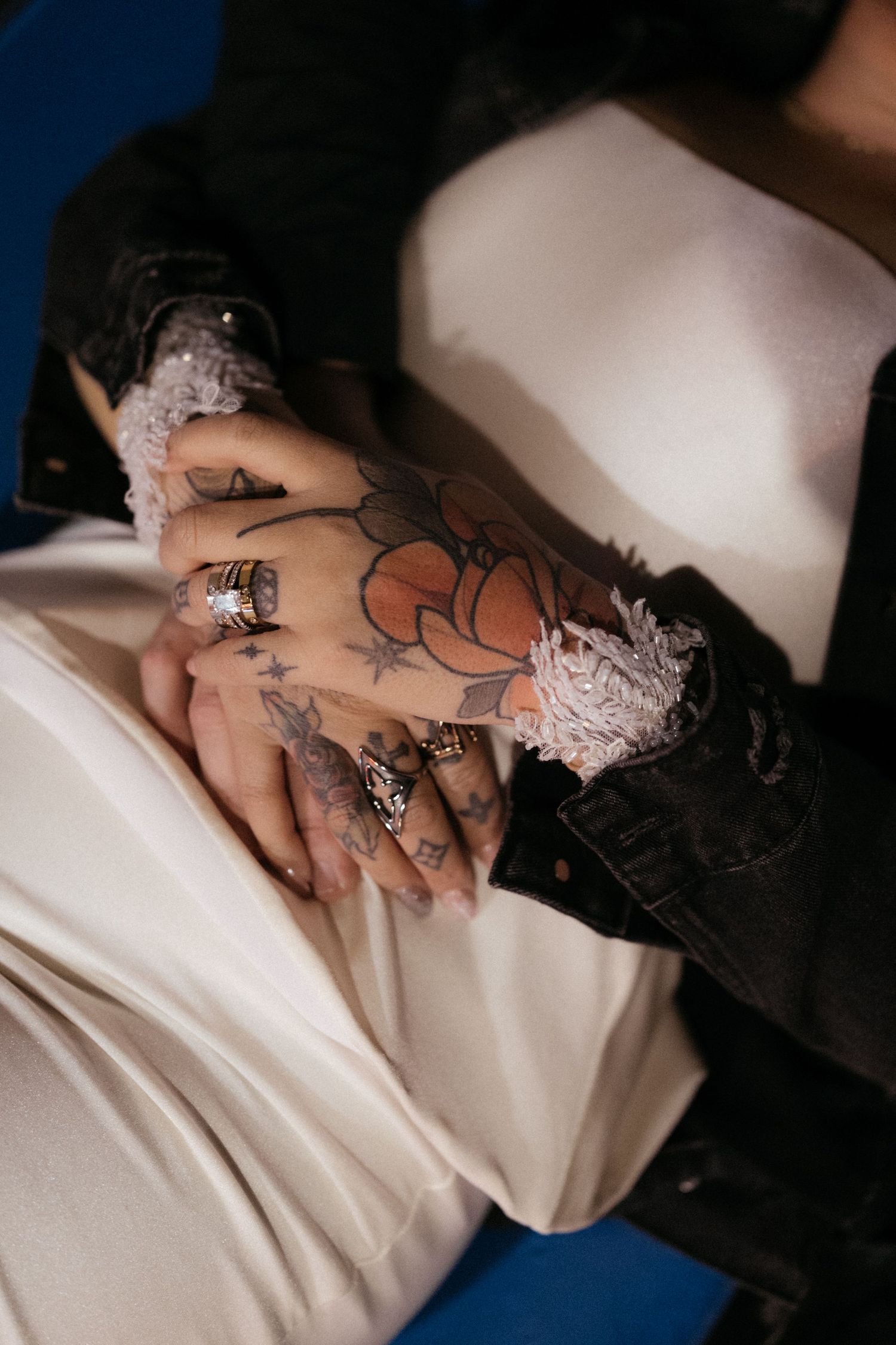 Close-up detail of lace and tattoos on fabric in moody lighting.