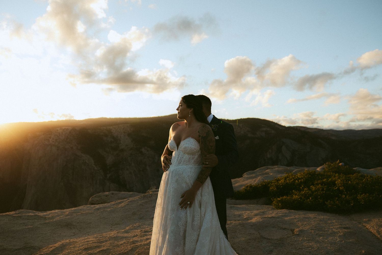 Bride and groom embrace during golden sunset at scenic rocky mountain overlook wedding elopement photo.