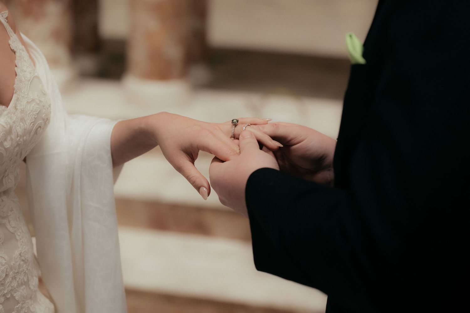 Close-up of hands during the ring exchange at a traditional church wedding ceremony.