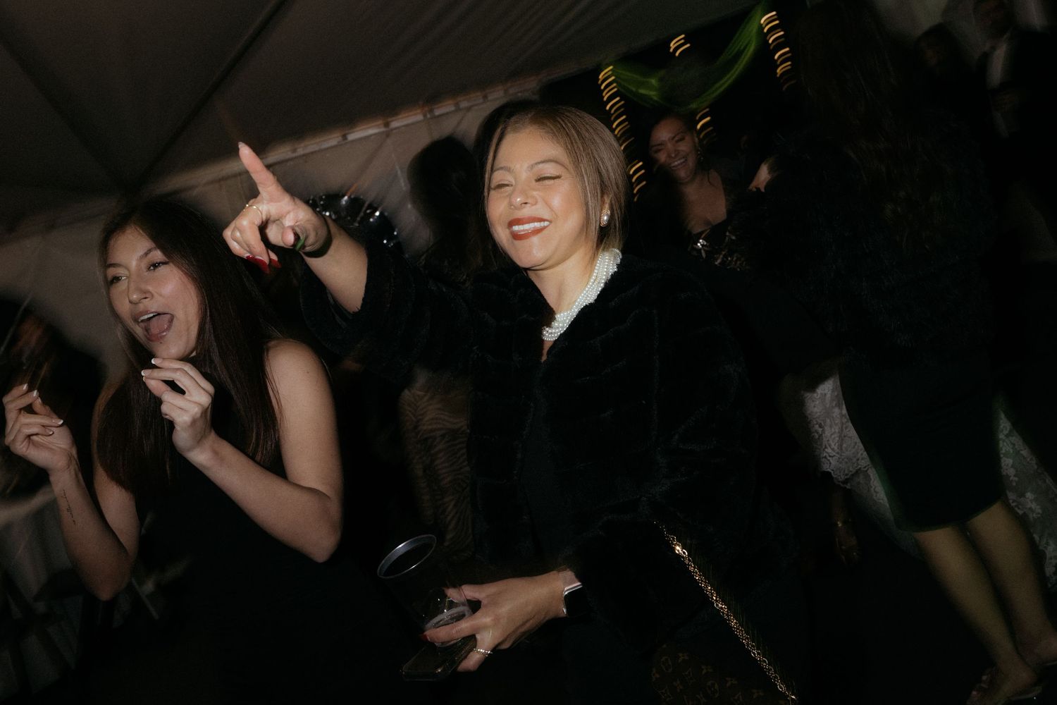 Dark party scene with people dancing and celebrating in a crowded space.
