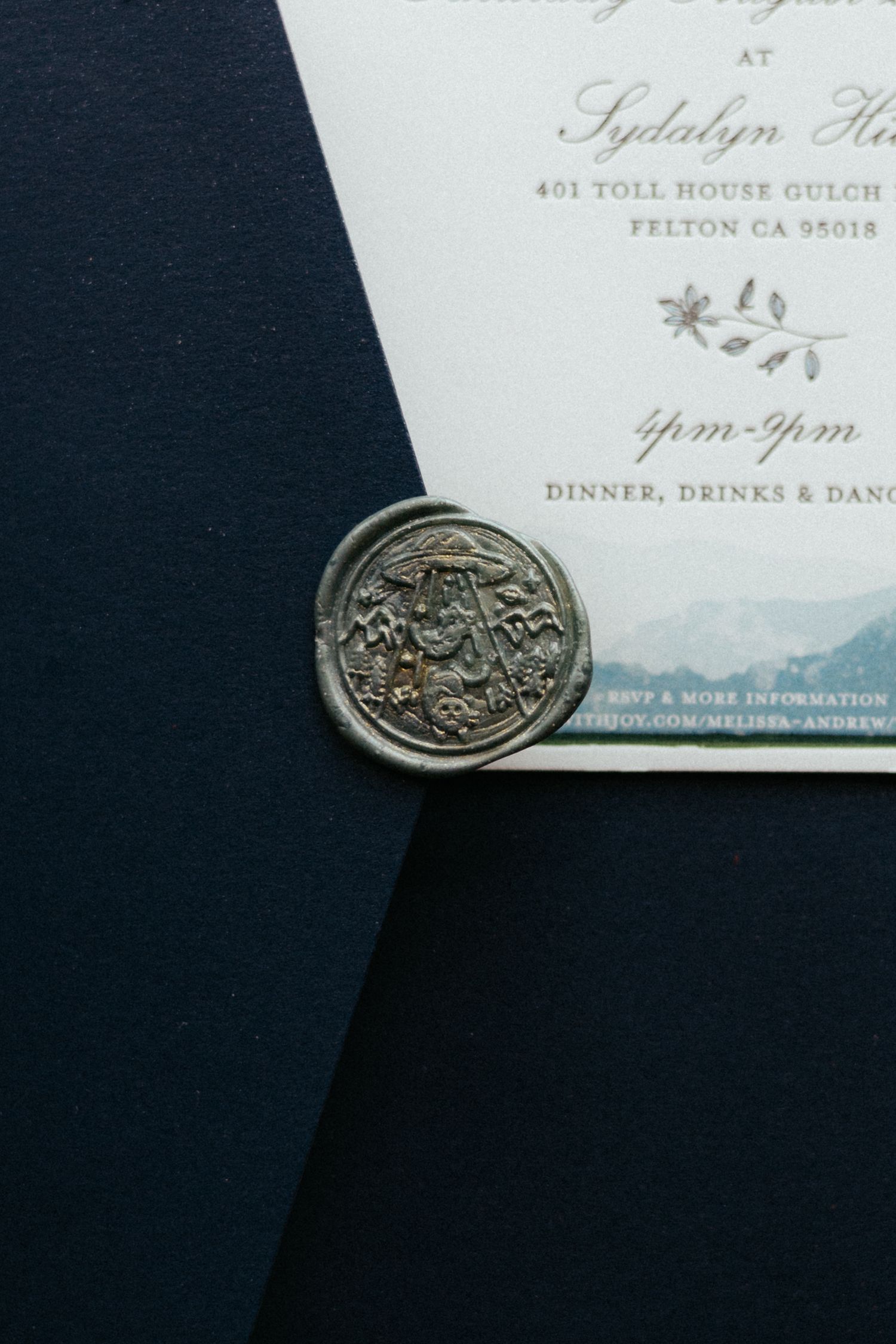 Elegant wedding invitation with decorative wax seal details shown against dark background.