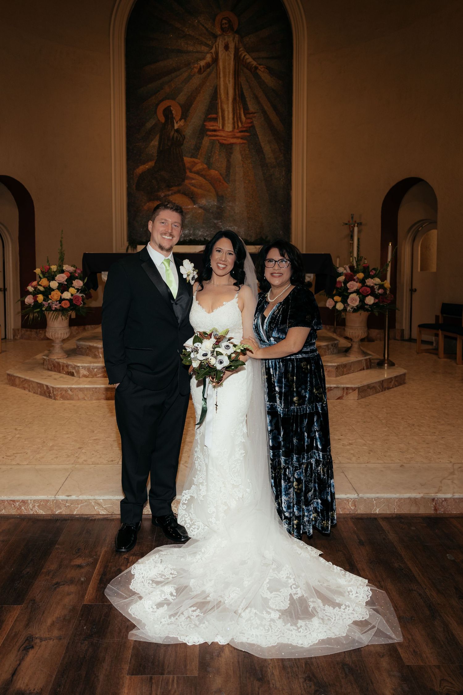 Wedding party poses together in elegant church setting with ornate altar and floral arrangements.