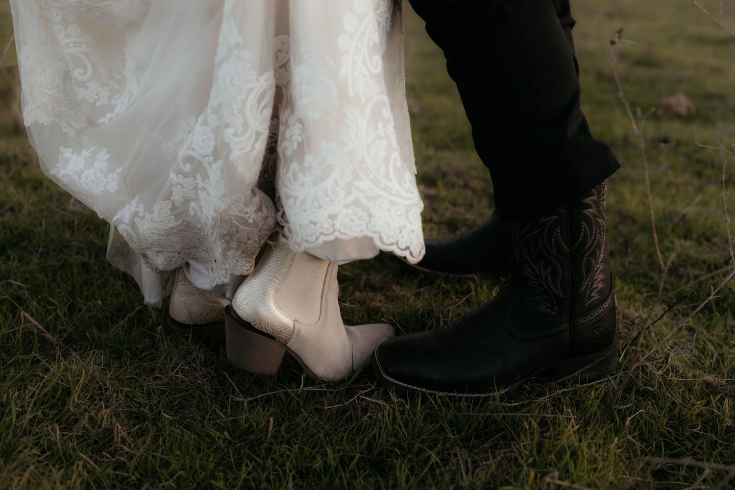 Close-up of bride and groom's feet, with her wearing cream heels and lace dress hem against his black dress shoes.