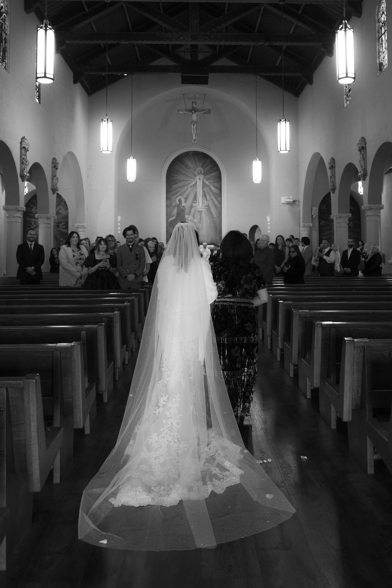 A long flowing veil trails down the aisle of a church during a wedding ceremony.