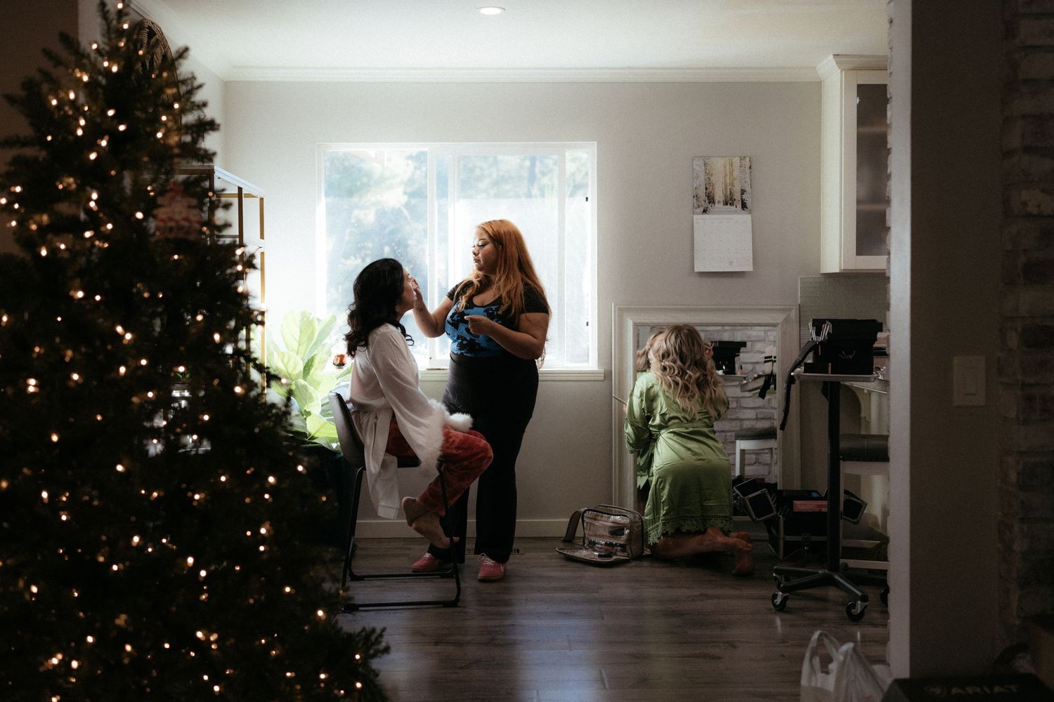 A living room decorated for Christmas with a lit tree and natural light streaming through windows.