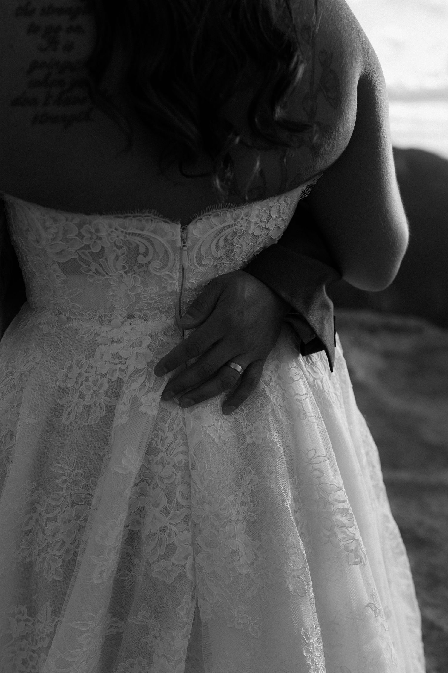 Bride in lace wedding dress with tattoos and diamond ring, black and white wedding photo.