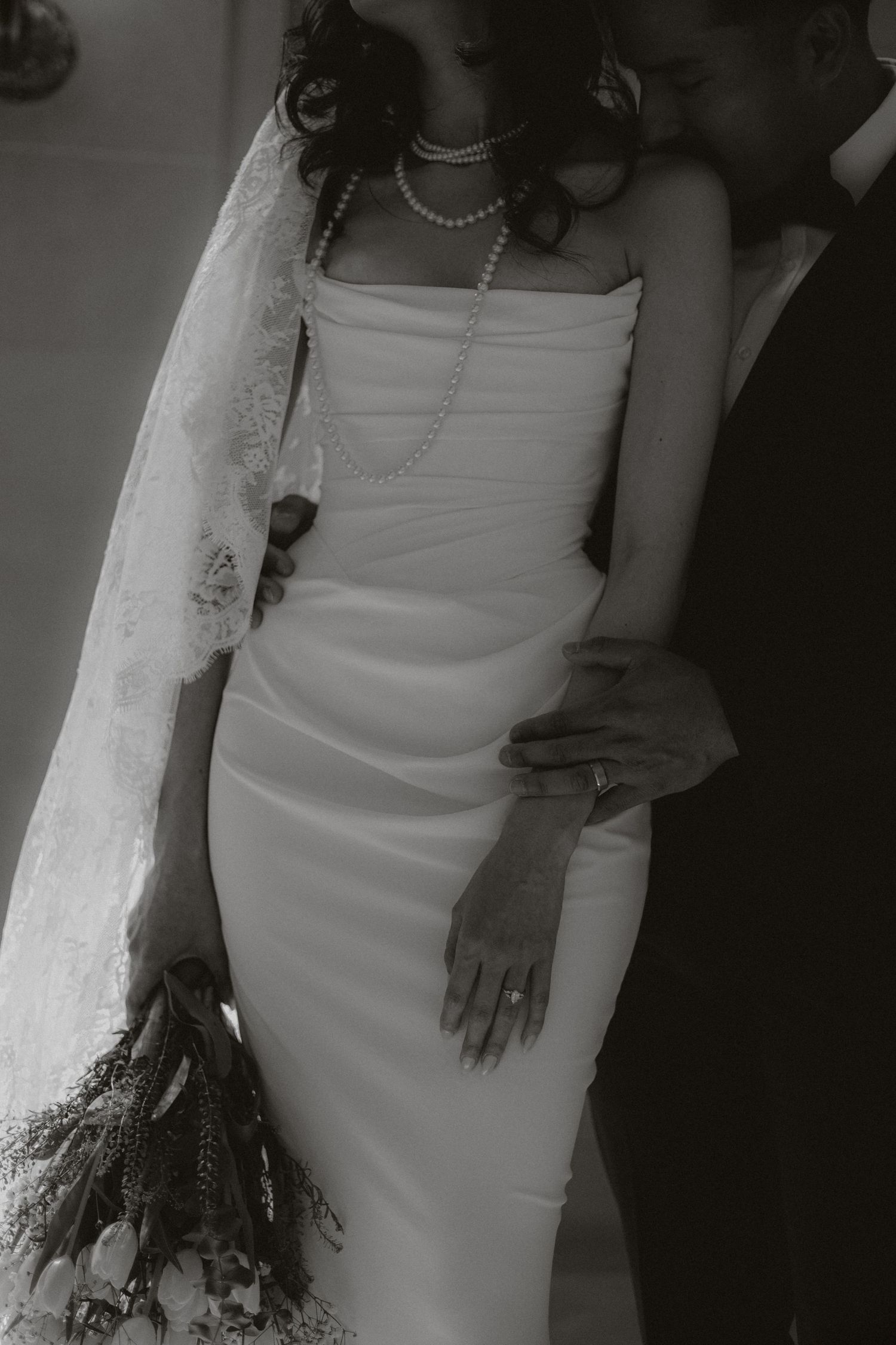 Elegant black and white detail shots of a bride's wedding dress and pearls.