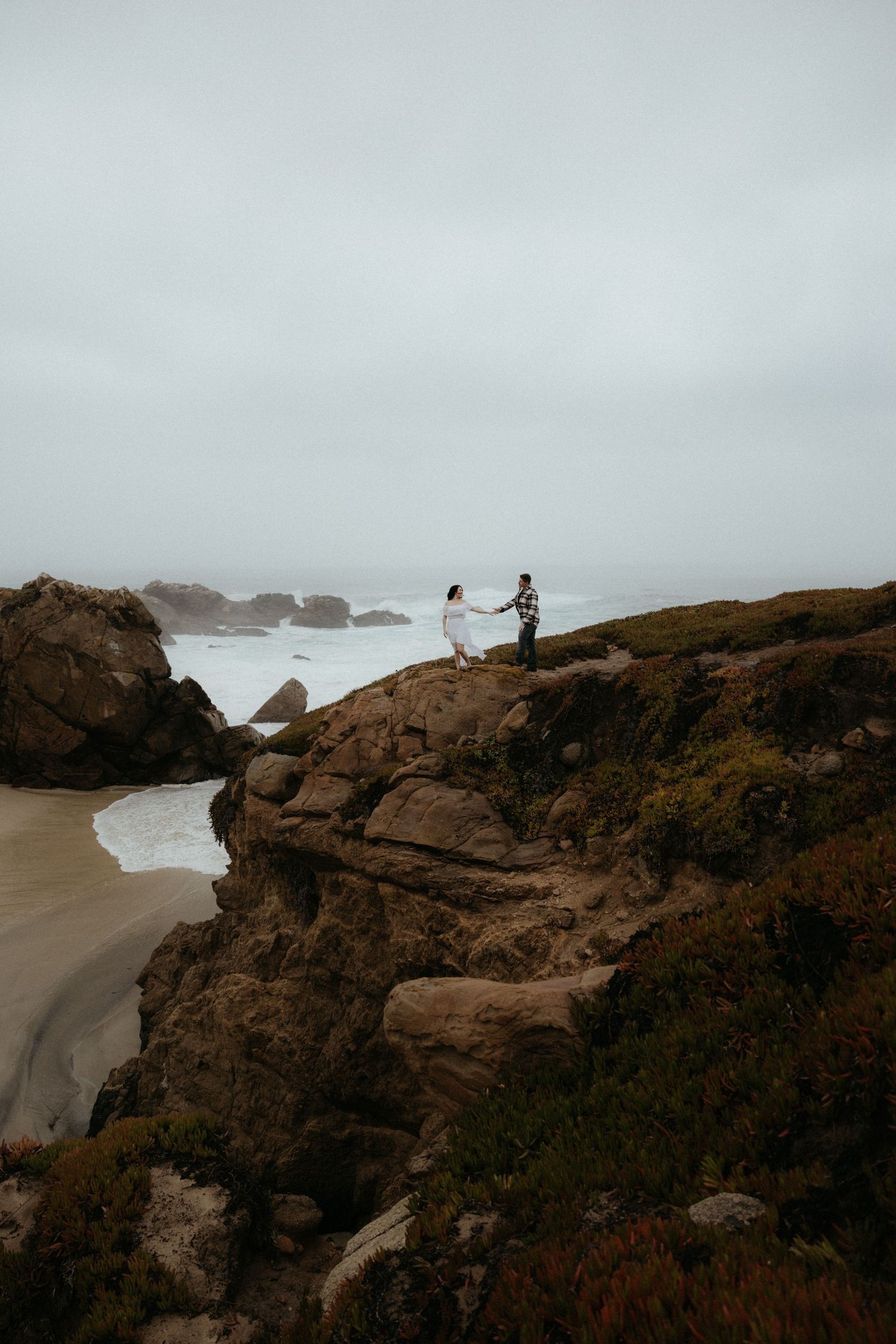 Moody coastal scene with rocky cliffs and dramatic ocean views under overcast skies.