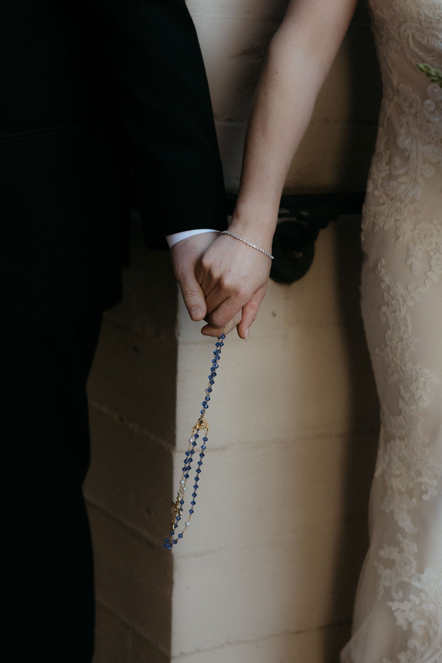 Close-up shots of hands holding rosary beads against a white wedding dress background.