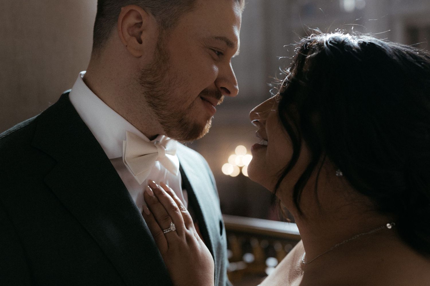 A romantic moment between newlyweds as they share an intimate close-up in soft lighting.