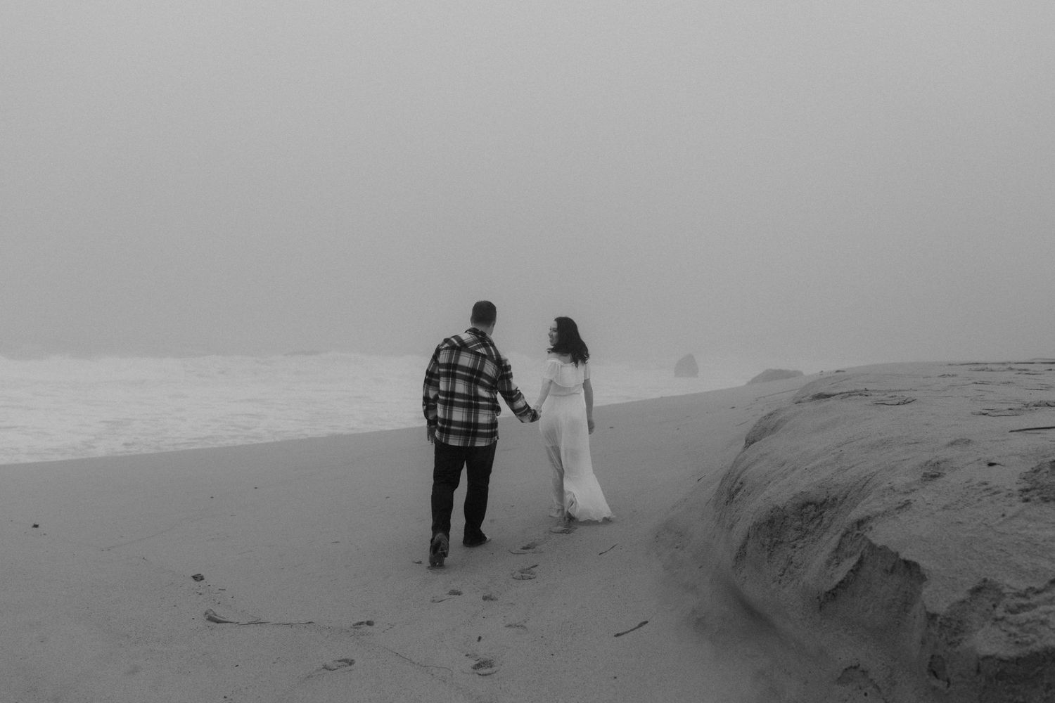 Two figures walk along dramatic coastal cliffs in moody weather.