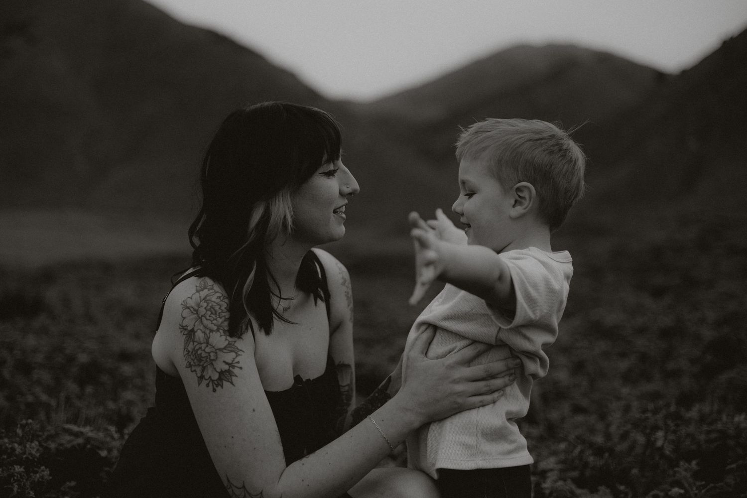 A tender family moment captured in black and white against a natural outdoor backdrop.