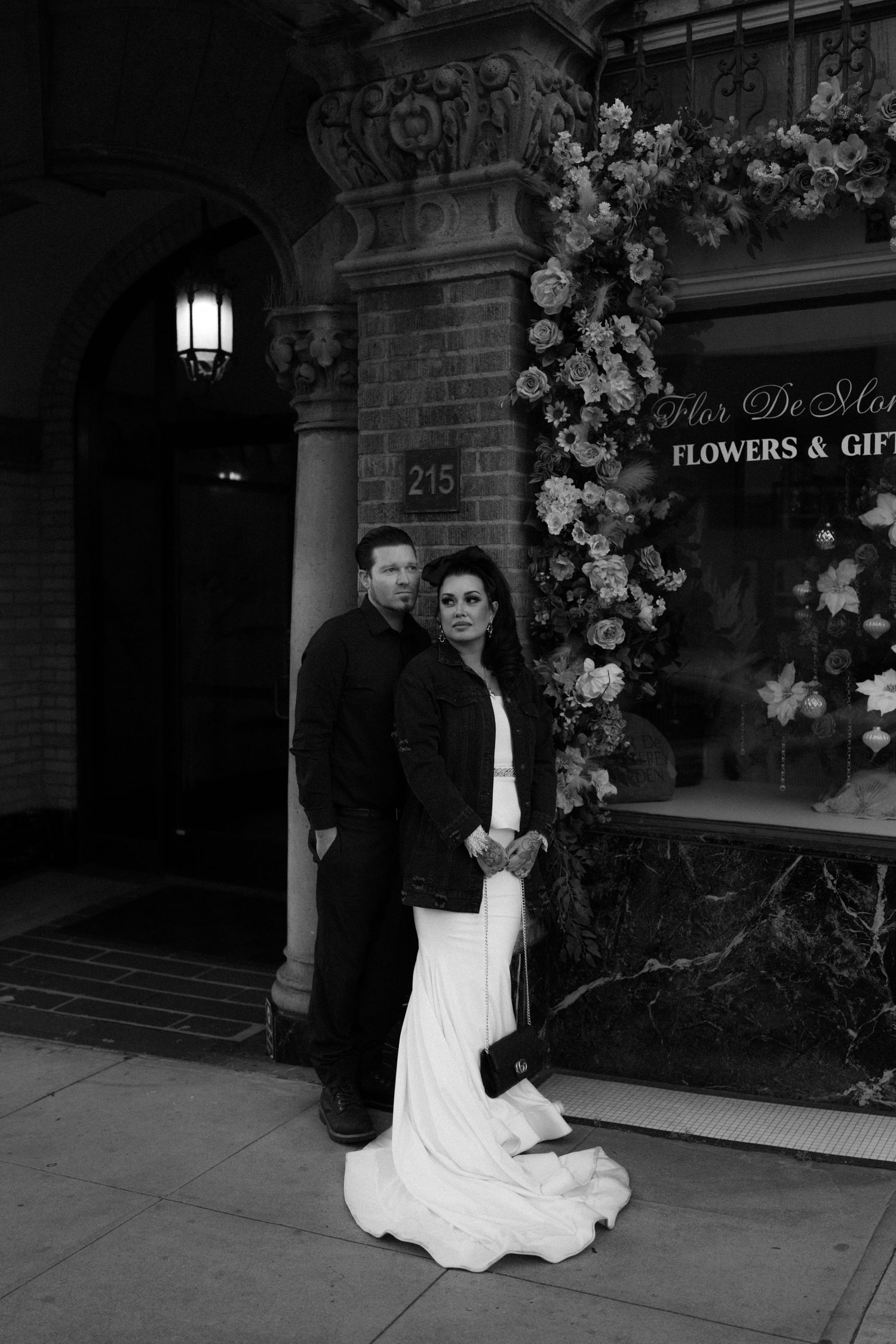 Black and white wedding photos showing a couple posing outside a flower shop entrance with floral decorations.