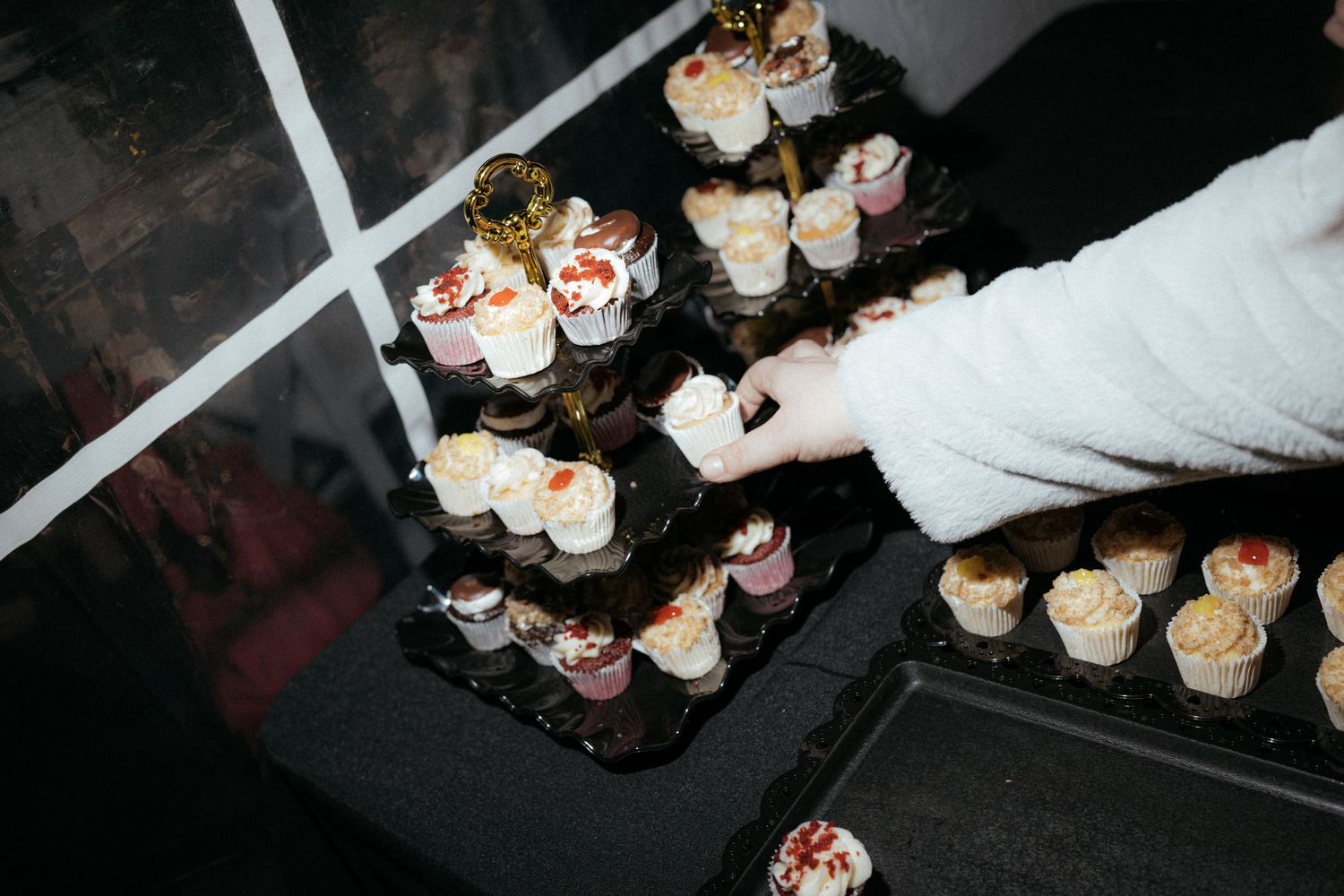 A tray of elegant dessert shooters with layered cream and toppings being arranged on a dark surface.