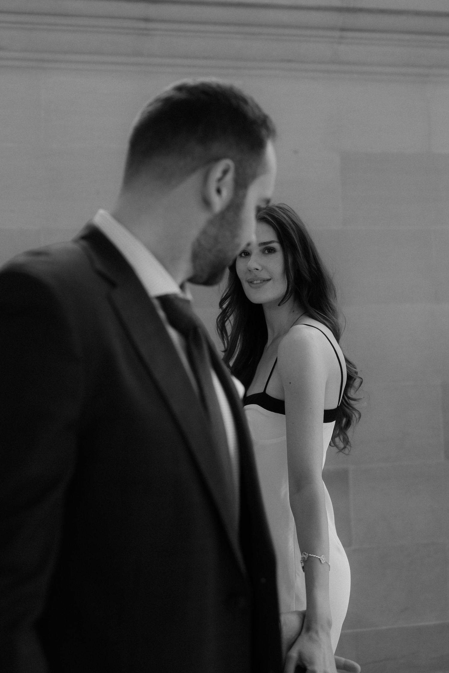 A series of black and white photos showing a couple in formal attire posing against a wall.